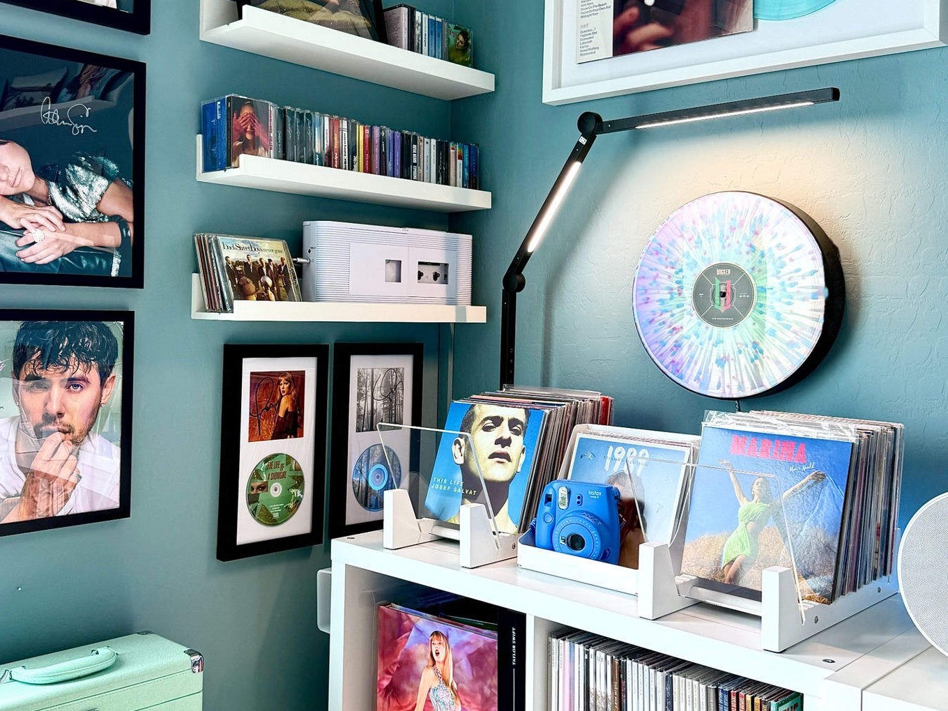 A Vylümi mounted on the wall beside a vinyl collection, record shelves, and turntable
